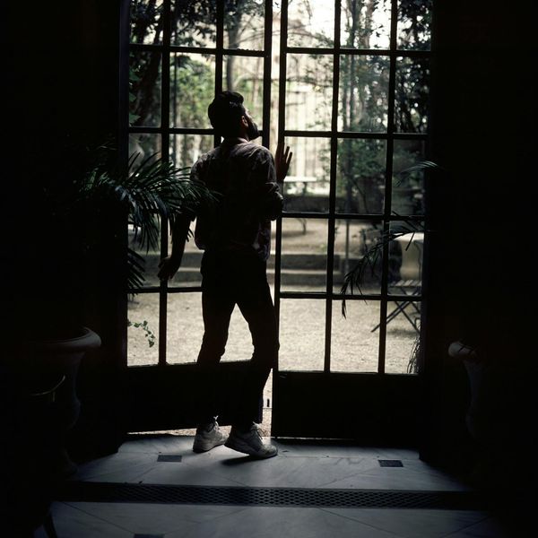 Silhouette of a man standing calmly, looking out over a quiet landscape.